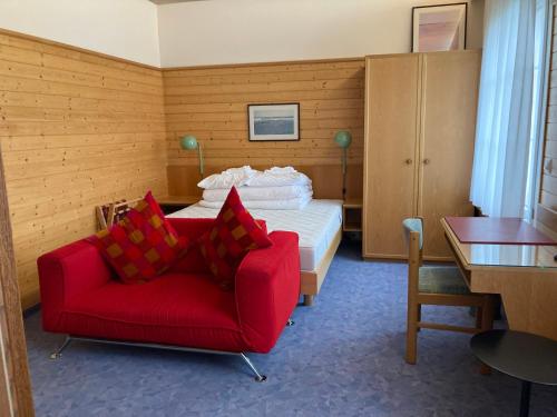 una camera con un divano rosso e un letto di FriendsHouse Appenzellerhof a Speicher
