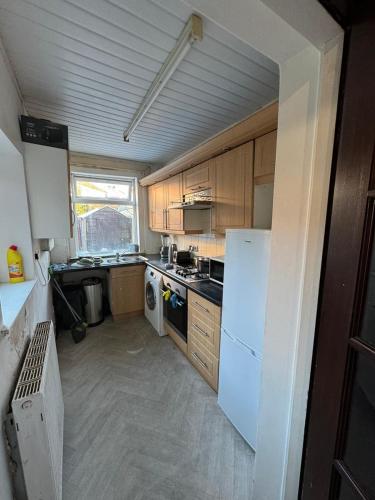 La cuisine est équipée d'un réfrigérateur blanc et de placards en bois. dans l'établissement 316 Ripponden home, à Moorside
