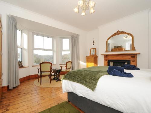 a bedroom with a bed and a fireplace and a mirror at Elmbank in Looe