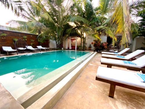 a swimming pool with lounge chairs and palm trees at CeZeRe THE PALM HOTEL in Paje