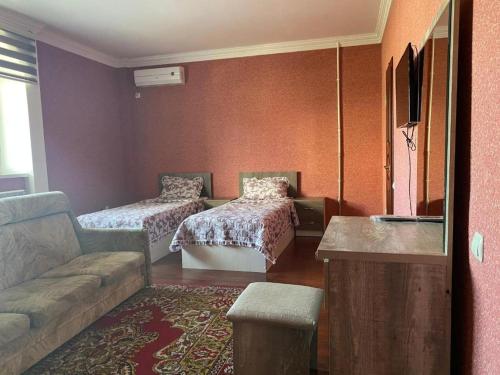 ein Wohnzimmer mit 2 Betten und einem Sofa in der Unterkunft Pamir Hotel-Hostel in Duschanbe