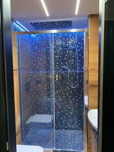 une salle de bain avec douche aux carreaux bleus dans l'établissement Vip apartment on the ski slopes, à Montgenèvre