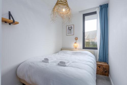 1 dormitorio con cama blanca y ventana en Gezellig appartement - Zeeparel - 6 personen - 3 kamers, en Middelkerke
