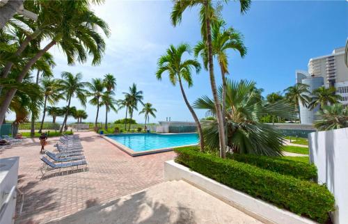 einen Pool mit Palmen und Liegestühlen in der Unterkunft Directly on the Beach with Pool & Ocean View in Miami Beach