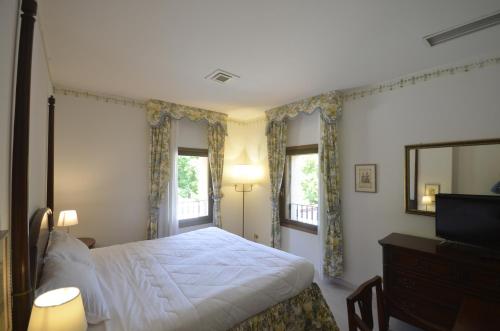 a bedroom with a bed and a television and windows at Hotel Villa Luppis in Pasiano di Pordenone