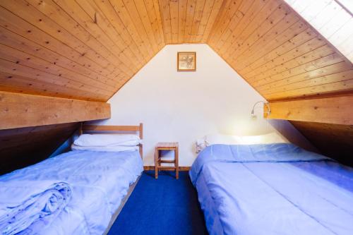 two beds in a room with a wooden ceiling at Appartement 5 pers in Saint-Sorlin-dʼArves