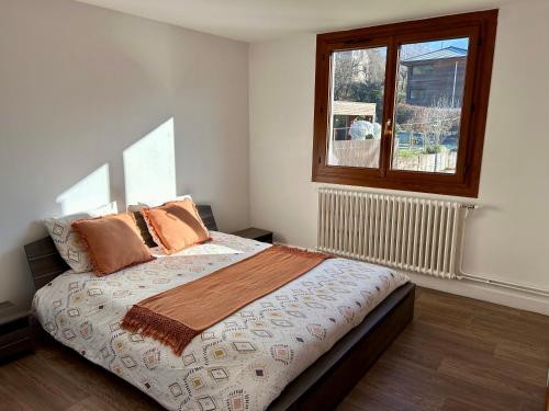 a bedroom with a bed with pillows and a window at Appartement au cœur des alpes in Albertville