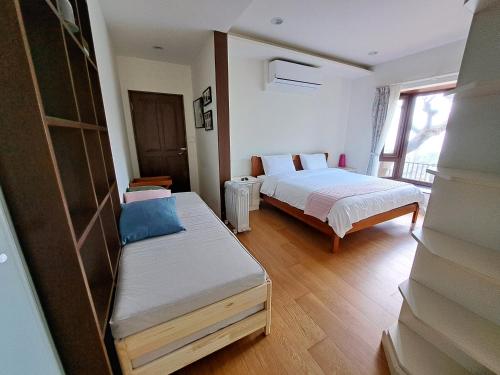 a bedroom with two beds and a bench in it at Mi Casa Homestay in Jiufen