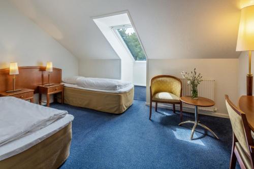 Cette chambre comprend deux lits, une table et une chaise. dans l'établissement Hotel Scheelsminde, à Aalborg