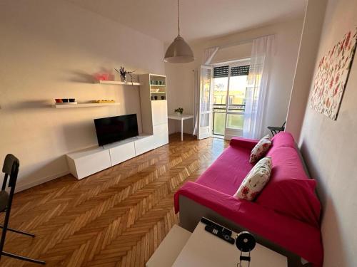 un soggiorno con un divano rosso e una TV di Kibilù - Via Lomellina MM Argonne - Linate Airport a Milano