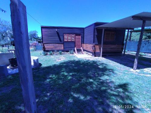 a small cabin with a grass yard with a pole at La Cautiva 225 in Villa del Dique