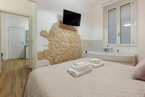 ein Schlafzimmer mit einem Bett, einer Badewanne und einem TV in der Unterkunft Fior Di Loto Rooms in Cagliari
