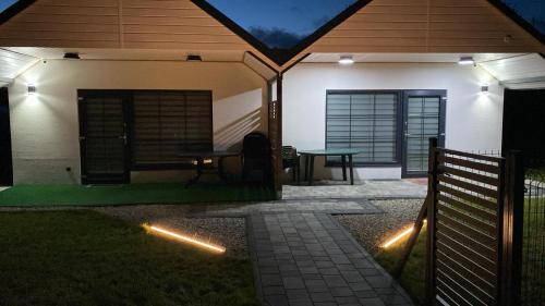 a house with a patio with a table and a fence at Domki Paradiese in Jarosławiec