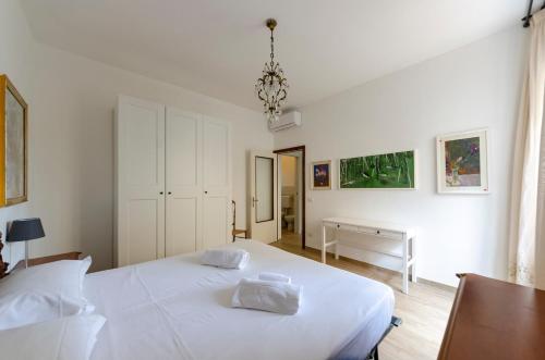 a white bedroom with a bed and a desk at Casa degli artisti 1 in Casarza Ligure