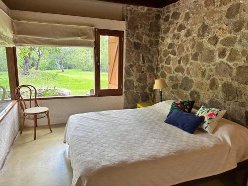 a bedroom with a large bed with a stone wall at Hermosa Casa de campo con pileta in Río Ceballos