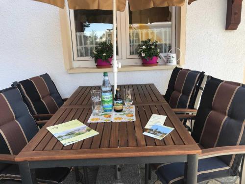 een houten tafel met flessen, glazen en stoelen bij Ferienwohnung Plötner in Bad Klosterlausnitz