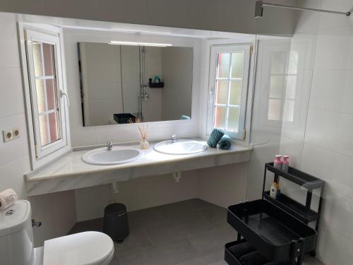 a bathroom with two sinks and a mirror and a toilet at Villa Venna, with a private pool in Baños y Mendigo