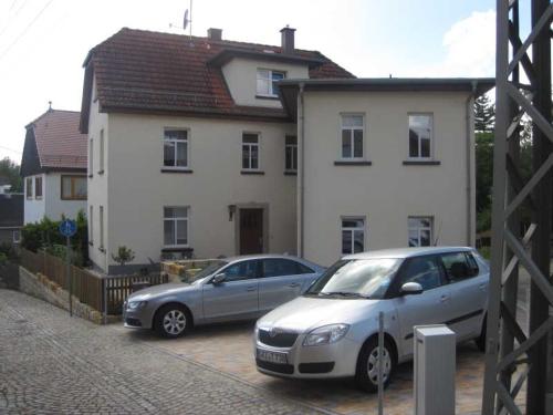 dos autos estacionados en un estacionamiento frente a una casa en Gästehaus Gimper, en Bad Klosterlausnitz