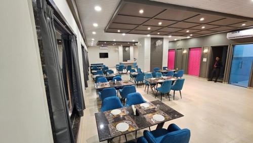 una sala conferenze con tavoli, sedie blu e una persona di Hotel Rajhans a Kondagaon