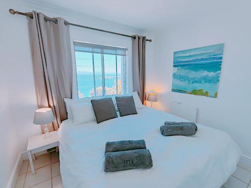 a bedroom with a white bed with two pillows on it at Bay Views in Simonʼs Town