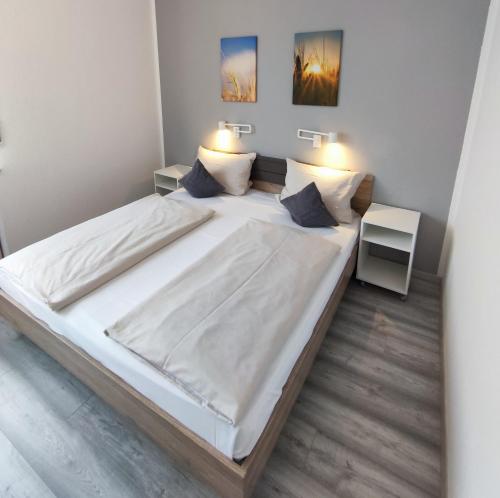 un grande letto bianco in una stanza con due lampade di Gästehaus am Bahnhof, Self Check In a Vechta