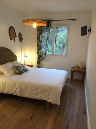 ein Schlafzimmer mit einem großen weißen Bett und einem Fenster in der Unterkunft Le jardin secret bnb in Villeneuve-lès-Béziers