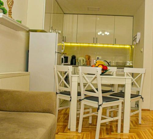 a kitchen with a white table and chairs and a refrigerator at Apartman Lux 5- private parking in Sombor