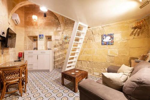 a living room with a staircase in a stone wall at Historic Hideaways - 900 Year Old Converted Studios in Victoria