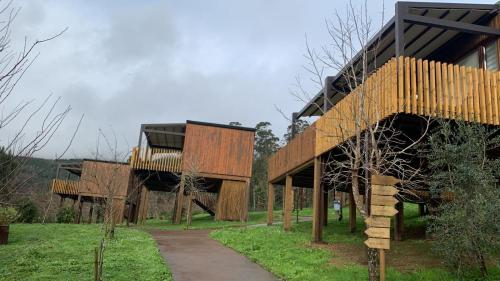 dos edificios de madera con un camino delante de ellos en Nidos de carnota, en San Mamede de Carnota