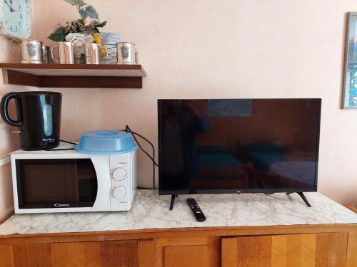un four micro-ondes assis sur un comptoir à côté d'une télévision dans l'établissement Studio pour 2 avec balcon, WiFi et parking à Brides-les-Bains - FR-1-512-226, à Brides-les-Bains