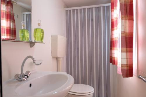 uma casa de banho com um lavatório branco e um WC. em Happy Camp mobilehomes in Camping Apollonia em Plakiás