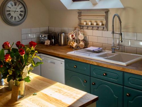 una cocina con fregadero y un jarrón de rosas sobre una mesa en The Barn, en South Cerney