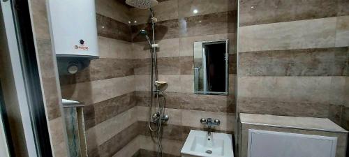 ein Bad mit einer Dusche und einem Waschbecken in der Unterkunft Апартамент Холидей in Razgrad