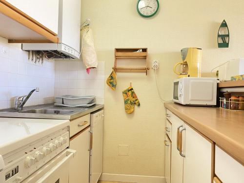 une cuisine avec un évier et un micro-ondes dans l'établissement 441 - A ERQUY, en bordure de la très belle plage de CAROUAL 2km de sables fin, à Erquy