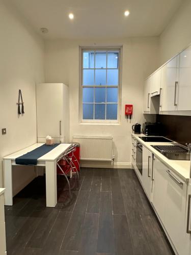 a white kitchen with a table and a window at London Regent Studio Apartments in London
