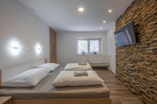 a bedroom with two beds and a stone wall at Apartmán Karin in Jihlava