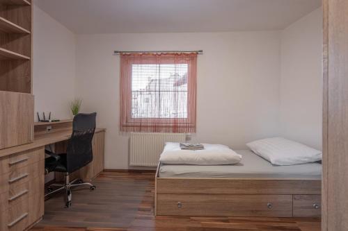 a bedroom with a bed and a desk and a window at Apartmán Karin in Jihlava