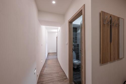 a hallway leading to a bathroom with a toilet and a mirror at Apartmán Karin in Jihlava