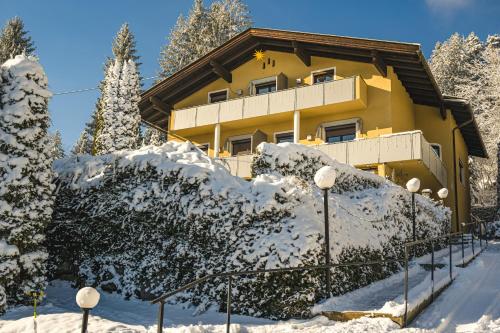 a building covered in snow with trees and lights at Waldvilla BERGSEE in Bodensdorf