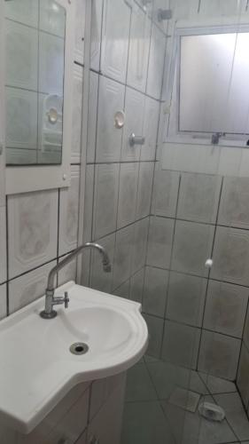 a white bathroom with a sink and a shower at Kit no Centrinho da Lagoa in Florianópolis