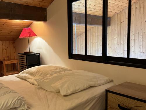 - une chambre avec un lit avec une lampe et 2 fenêtres dans l'établissement Studio cosy aux Gets, proche télécabines, balcon exposé Sud-Ouest, idéal pour 4 personnes - FR-1-671-63, aux Gets