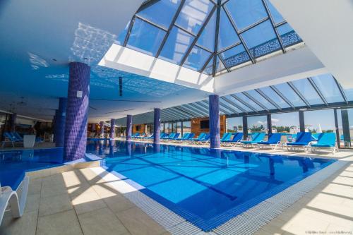 a large swimming pool with blue chairs in a building at Etno selo Stanišići Hotel Leonida in Dijelovi