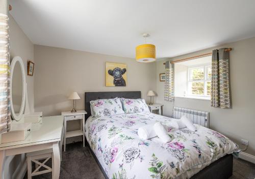 um quarto com uma cama, uma secretária e uma janela em Hobsons Cottage em Grinton