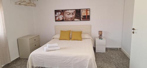 - une chambre blanche avec un lit blanc et des oreillers jaunes dans l'établissement La Cantora, à Sagonte