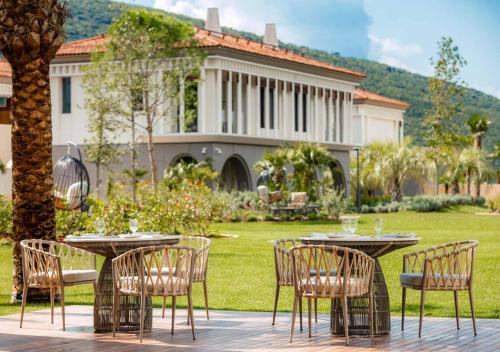 a patio with tables and chairs in front of a house at One&Only Portonovi in Herceg-Novi