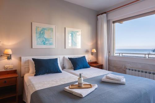 a bedroom with two beds with blue pillows and a window at Pensión Zarauz Playa in Zarautz