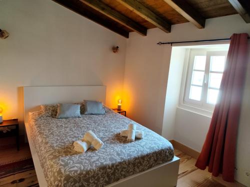 um quarto com uma cama com duas almofadas e uma janela em Casa Nº7 - Vila de Óbidos em Óbidos