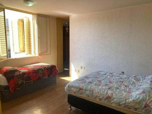 1 dormitorio con 2 camas, ventana y falda en Solar dos Costais: casa com 4 suítes climatizadas en Uberaba
