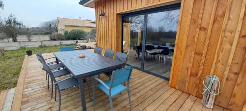 une terrasse en bois avec une table et des chaises dessus dans l'établissement Agréable villa neuve orientée vers la nature et le coucher de soleil!, au Le Verdon-sur-Mer