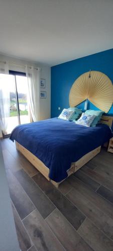 een slaapkamer met een groot bed met een blauwe muur bij Agréable villa neuve orientée vers la nature et le couché de soleil! in Le Verdon-sur-Mer